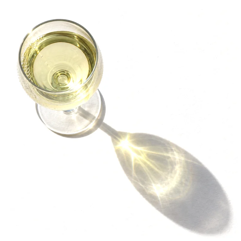 A glass of vinho verde casting a long shadow